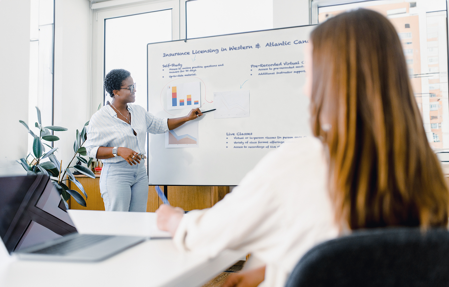 Instructor delivers lecture next to whiteboard