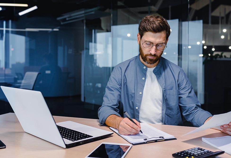 Un homme travaille à côté de son ordinateur portable dans un bureau.