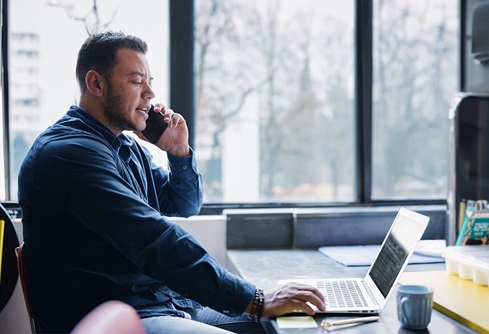 Man at desk on phone and laptop