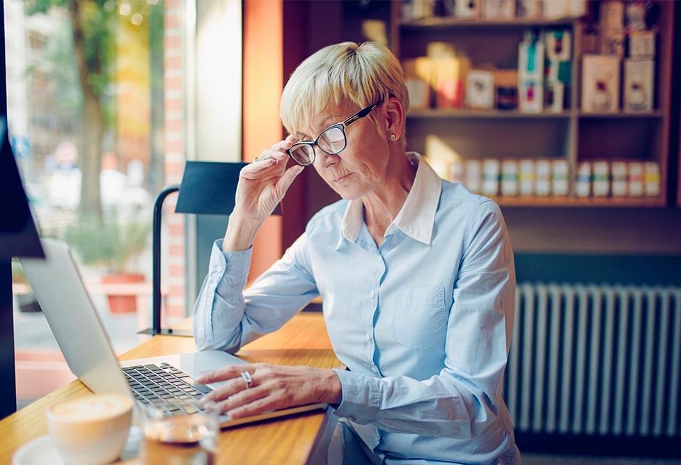 Woman in glasses stares intently at laptop screen