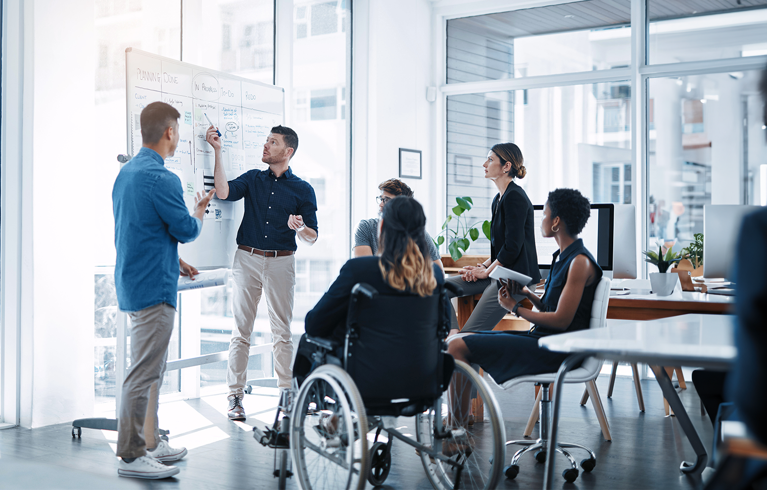 Two men present to peers with aid of whiteboard
