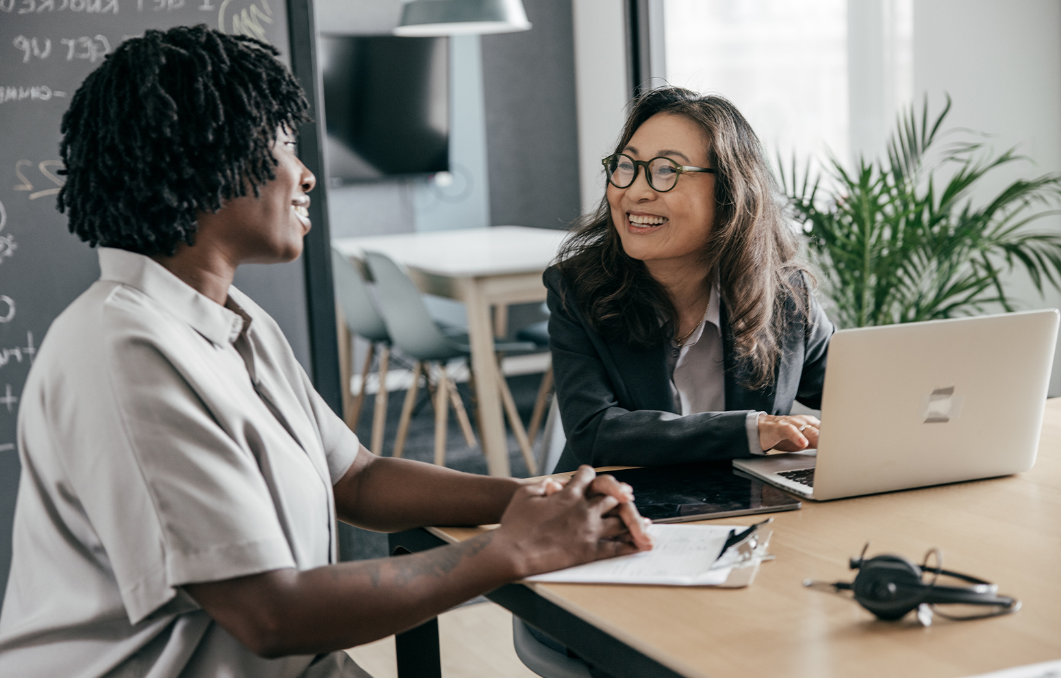 Deux femmes discutent en étant assises devant un ordinateur.