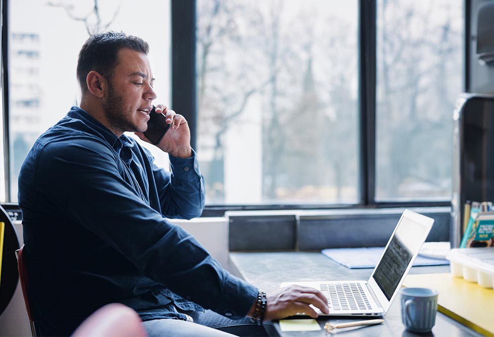 Man at desk on phone and laptop
