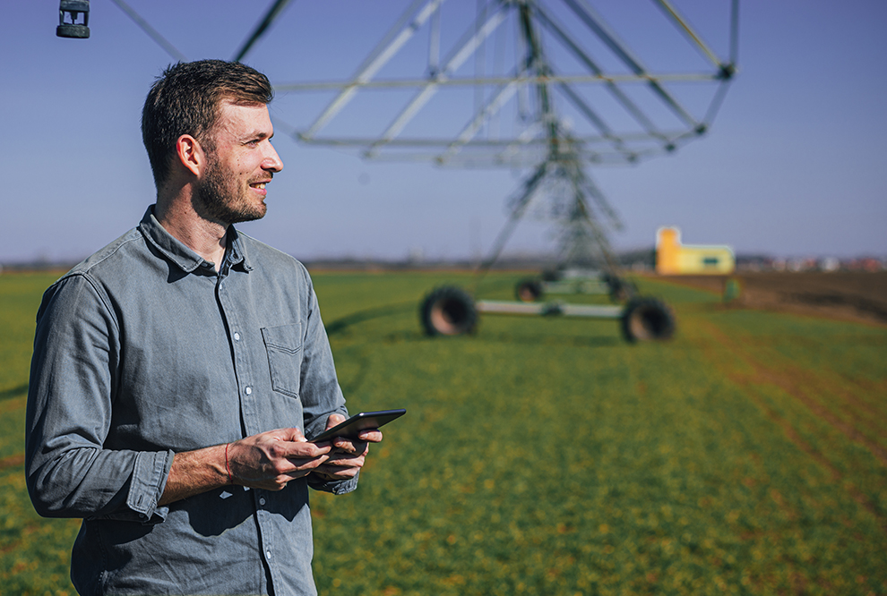 Man stands on farm while using cellphone.