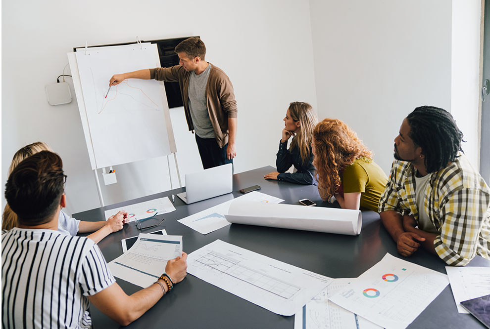 Man works on white board during a meeting. 