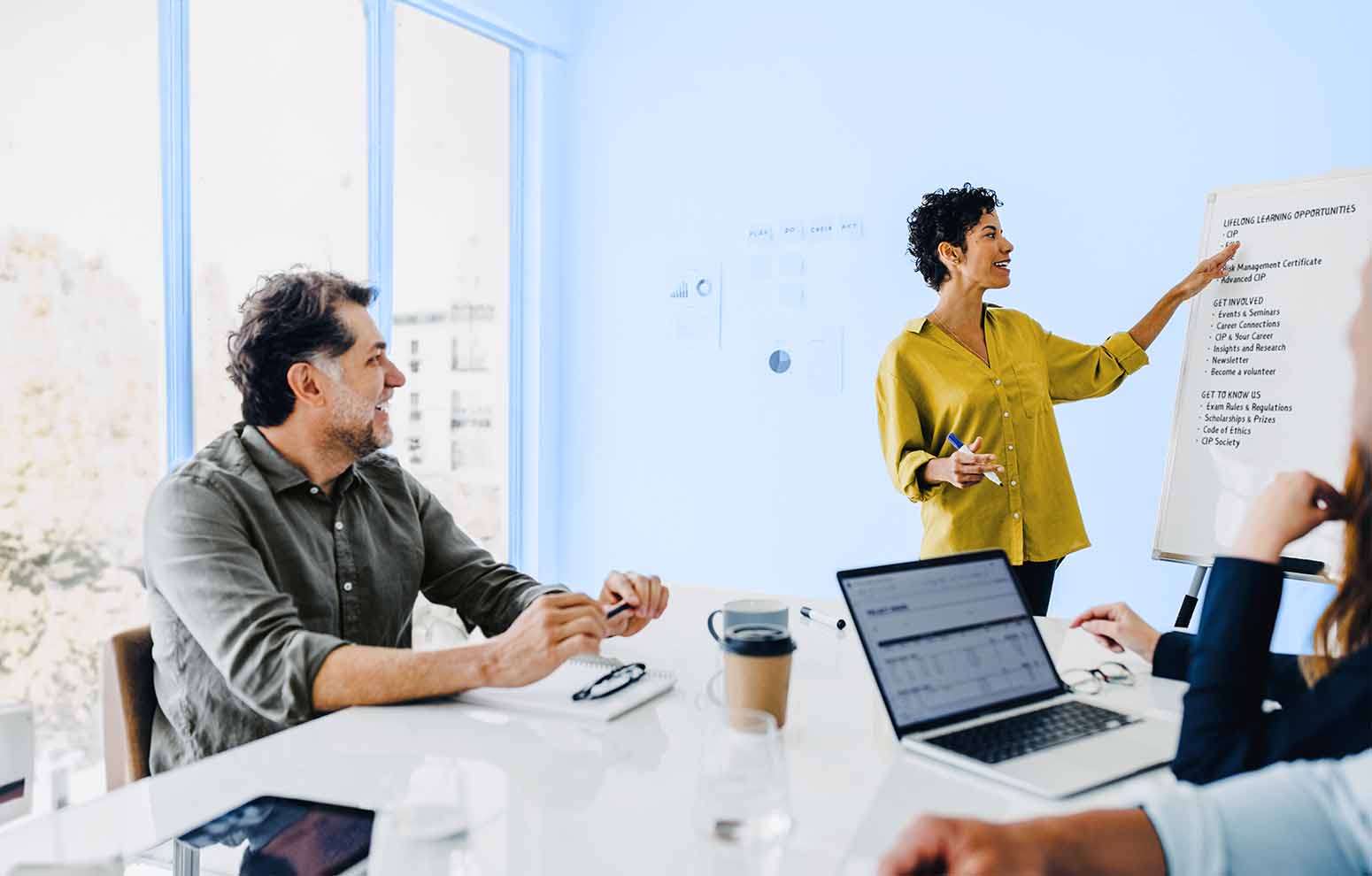 Woman stands at the board while teaching a seated man
