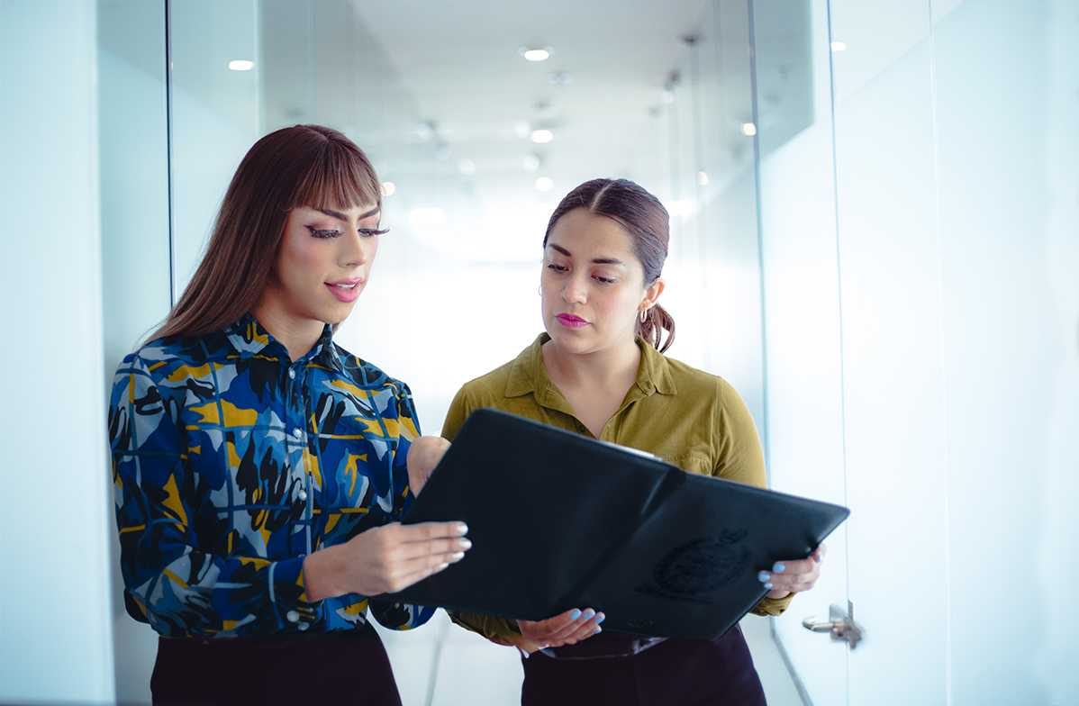Two woman look at a document.