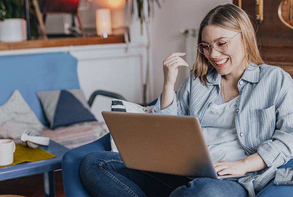 Une femme sourit en utilisant l'ordinateur.
