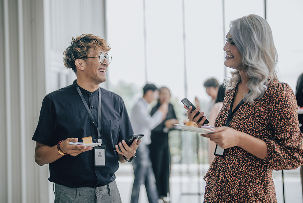 Coworkers talking while holding cell phones. 