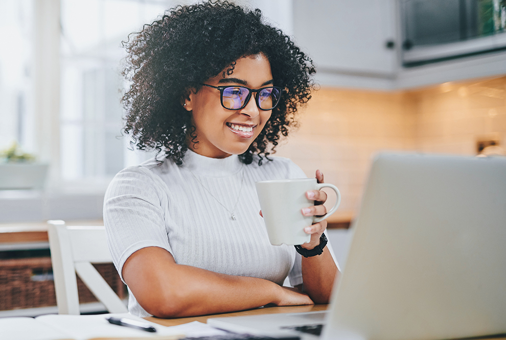 Une femme sourit en travaillant sur l'ordinateur.