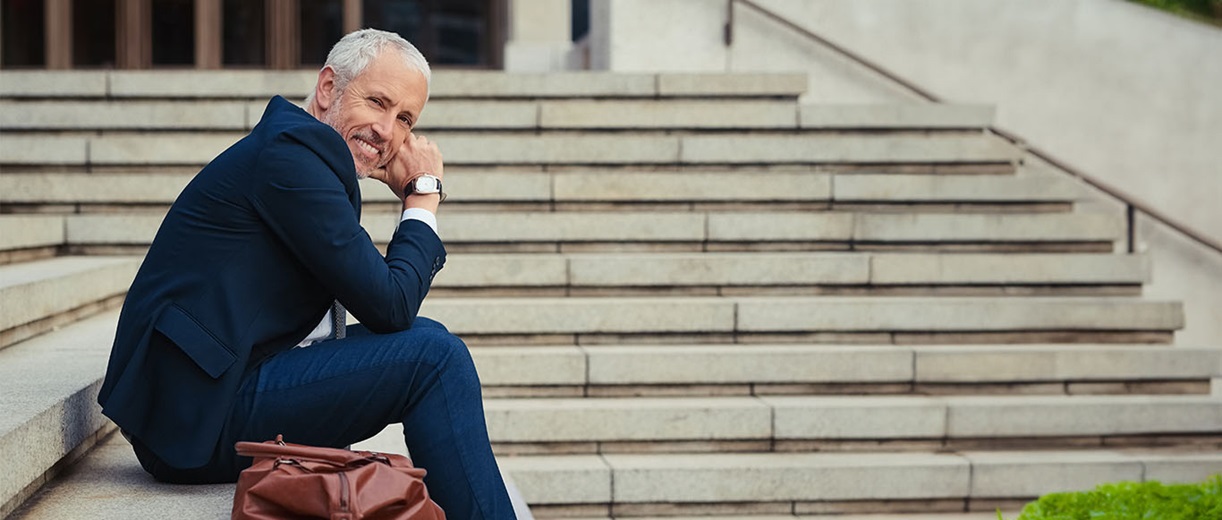 A man in a blue blazer sitting on steps