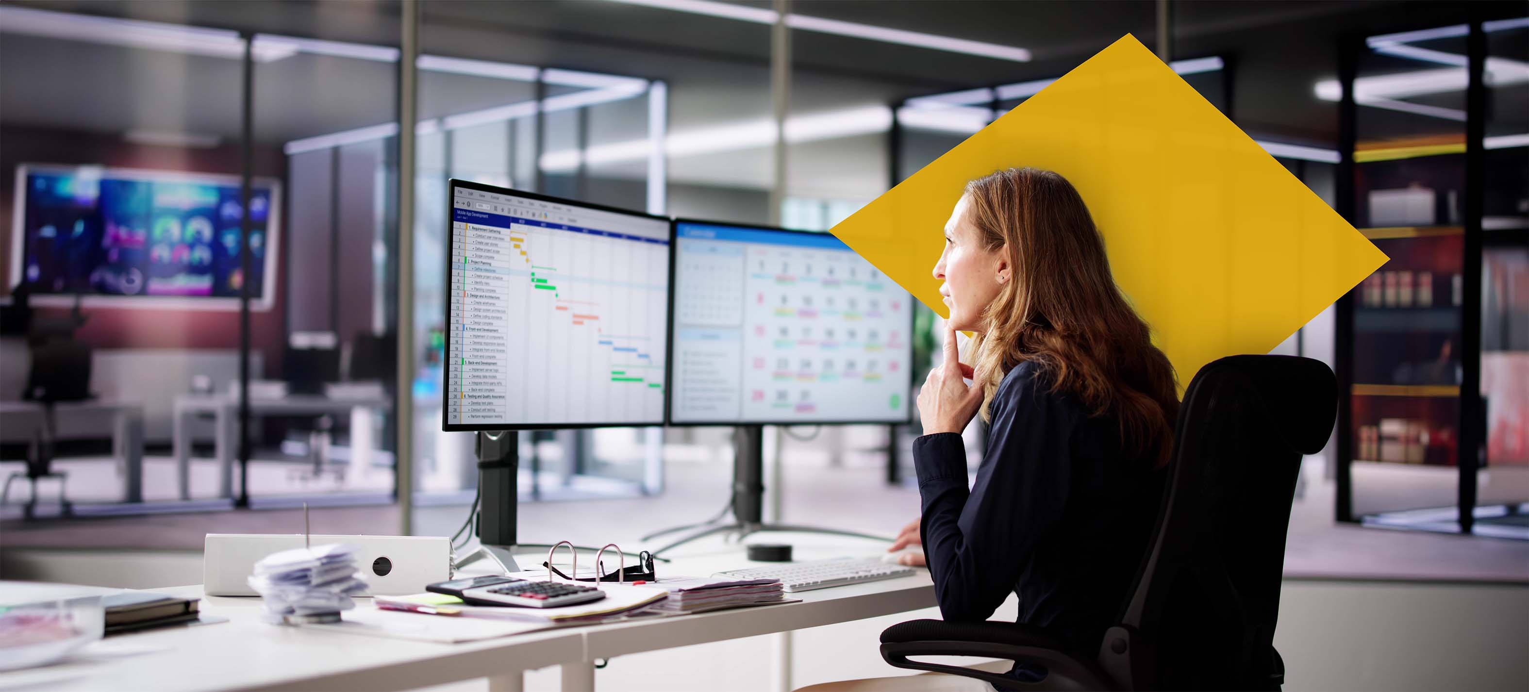 Woman working in office looking at multiple screens